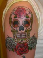 Tatuaje en el brazo de una calavera de azúcar Mexicana con tres rosas