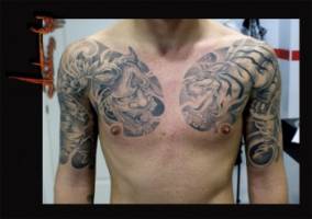 Tatuaje en blanco y negro de un tigre y hanya en ambos pectorales de un chico