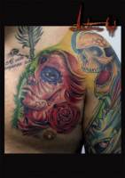 Tatuaje en el pecho de una chica pintada  de calavera mexicana en el pecho junto con una roas y una calavera