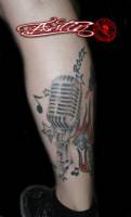 Tatuaje de un micrófono con estrellas y notas musicales