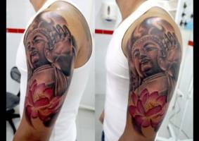 Tatuaje a color de una estatua de buda  y una flor de loto
