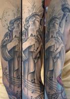 Tatuaje en el brazo de la estatua de la libertad, con la llama de notas musicales