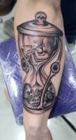 Tatuaje de un reloj de arena con un bebe dentro y un esqueleto