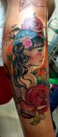 Tattoo old school de una chica con gorra, rosas y un tintero con pluma de escribir