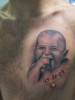 Tattoo de un bebé en el pecho, con una fecha