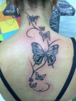Tatuaje de mariposas una tallo de planta en la columna de una chica