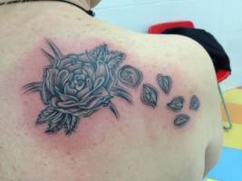 Tatuaje de una rosa dejando ir pétalos 
