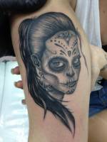 Tatuaje de una chica con pendientes pintada de calavera mexicana