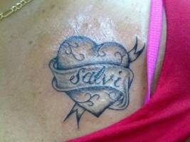 Tatuaje de un corazón y una cinta con el nombre salvi