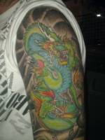 Dragón a color tatuado en el brazo