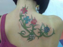 Tatuaje de una planta con flores en la espalda