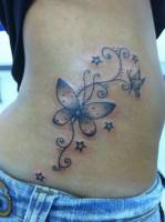 Tatuaje de una planta con mariposas y estrellas en la cintura