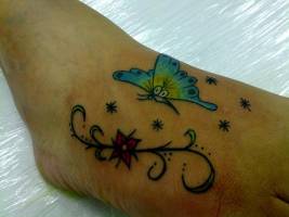 Tatuaje de una mariposa bajo las estrellas volando hacia una flor
