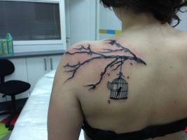 Tatuaje de una jaula abierta, colgando de una rama