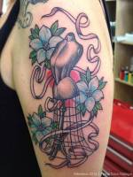 Tatuaje de un maniquí entre flores y cintas de costura