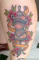 Tatuaje de un maniquí, con un vestido, una cinta de costura y flores