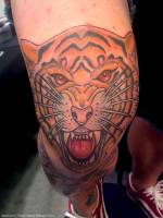 Tatuaje de una cara de tigre rugiendo en la pierna