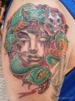 Tatuaje de una cara llorando sangre, con serpientes y calaveras alrededor