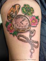 Tatuaje de un reloj de bolsillo con un trébol y varias flores