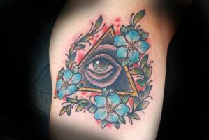 Tattoo del ojo que todo lo ve entre laureles y flores