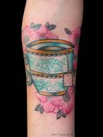 Tatuaje de una taza de té entre flores
