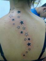 Tatuaje de una línea de estrellas recorriendo la columna