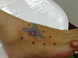 Tatuaje de una mariposa volando bajo las estrellas