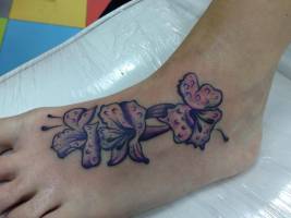 Tattoo de unas flores con gotitas de agua en el pie