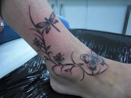 Tattoo de una mariposa y una libélula junto a una planta con flores