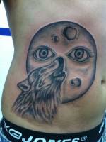 Tatuaje de un lobo aullando a una luna con ojos
