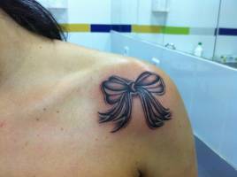 Tatuaje de un lazo en el hombro de una chica
