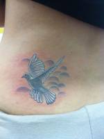 Tatuaje de una paloma volando en el cielo