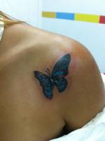 Tatuaje de una mariposa en color tatuada en el hombro de una chica