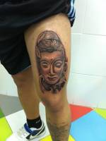 Tatuaje de una cara de buda tatuada en la pierna