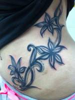 Planta con flores tatuado en la cintura de una chica