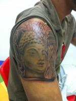 Cara de buda junto a bambu tatuado en el brazo