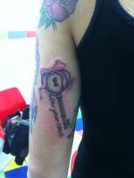 Tatuaje de una llave con forma de corazón con un lazo