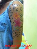 Brazo tatuado como un leopardo y flores a color en el medio