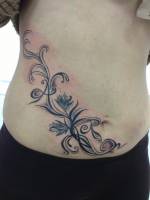 Tatuaje de plantas en la cadera y barriga de una chica