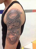 Brazo tatuado con un dragón en blanco y negro