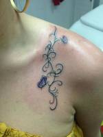 Tatuaje de una enredadera en la clavícula con unas mariposas
