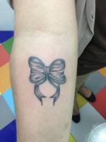 Tatuaje de un lazo en el antebrazo de una chica