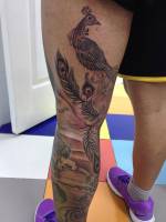 Tatuaje blanco y negro de un pavo real en la pierna
