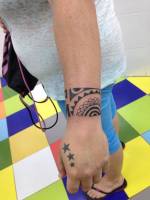 Tatuaje de un brazalete maorí en el brazo y algunas estrellas en la mano de una mujer