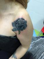 Tatuaje de una rosa negra en el hombro de una chica
