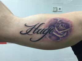 Tatuaje de una rosa y el nombre Hugo
