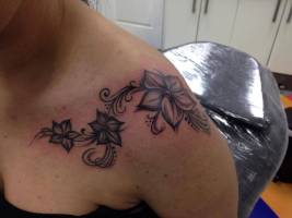 Flores tatuadas en el hombro de una mujer