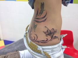 Flores y mariposas tatuadas en la espalda de una chica