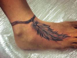 Tatuaje de una pulsera con una pluma atada