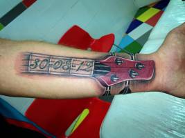 Tatuaje del mango de una guitarra con una fecha
